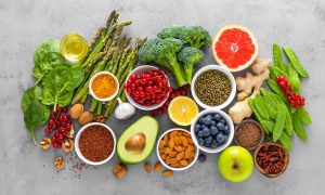 Healthy food background, spinach, quinoa, apple, blueberry, asparagus, turmeric, red currant, broccoli, mung bean, walnuts, grapefruit, ginger, avocado, almond, lemon, green peas and goji, top view